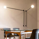 Nemo Potence Pivotante Wandlampe 200cm an einer Wand über einem Tisch mit modernen Stühlen.