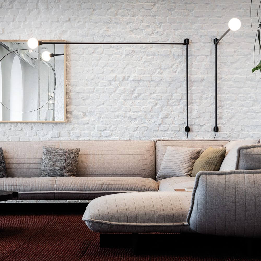 Nemo Potence Pivotante Wandlampe 200cm an einer Wand über einem modernen Sofa in einem stilvollen Wohnzimmer
