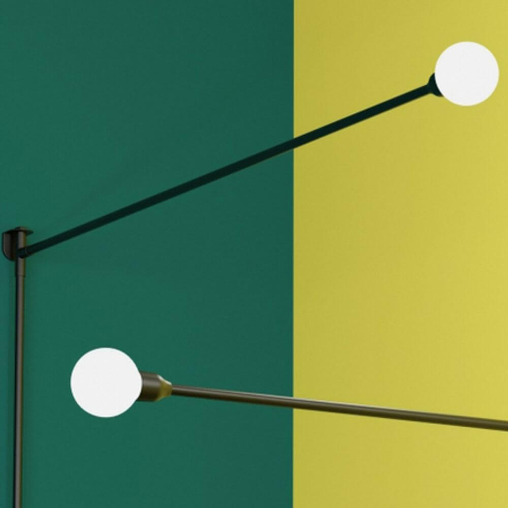 Nemo Potence Pivotante Wandlampe 200cm mit zwei Kugellampen an farbigen Wänden.
