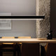 Nemo Tru Horizontal Up+Down LED Hängeleuchte über modernem Esstisch mit skandinavischen Stühlen.