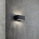 Nene LED Außen-Wandleuchte IP54 Schwarz an einer Wand aus Beton, strahlt sanftes Licht nach oben und unten.