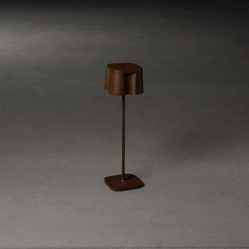 Nice LED Outdoor USB-Tischlampe CCT in Rostfarben auf einem grauen Untergrund.