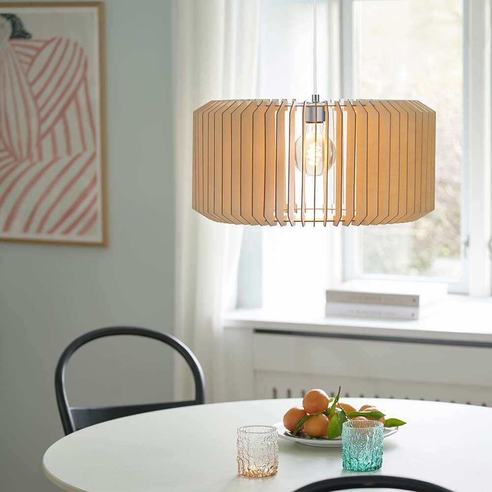 Asti Hängeleuchte Holz Ø 50cm über einem Tisch mit Früchten und Gläsern, Designerlampe mit Holzlamellen.