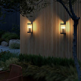 Coupar Außenwandleuchte an einer Holzwand, sanftes Licht strahlt in modernen Gartenbereich.