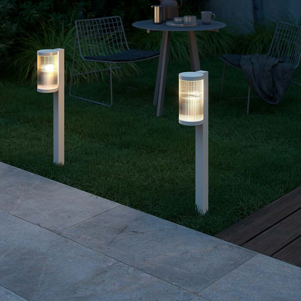 Coupar Pollerleuchte IP54 im Garten mit sanftem Licht und modernem Design, ideal für stimmungsvolle Beleuchtung.