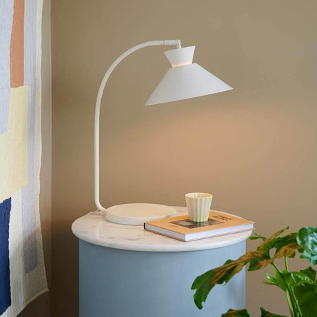 Dial bordlampe på sidebord med geometrisk design og varmt lys.