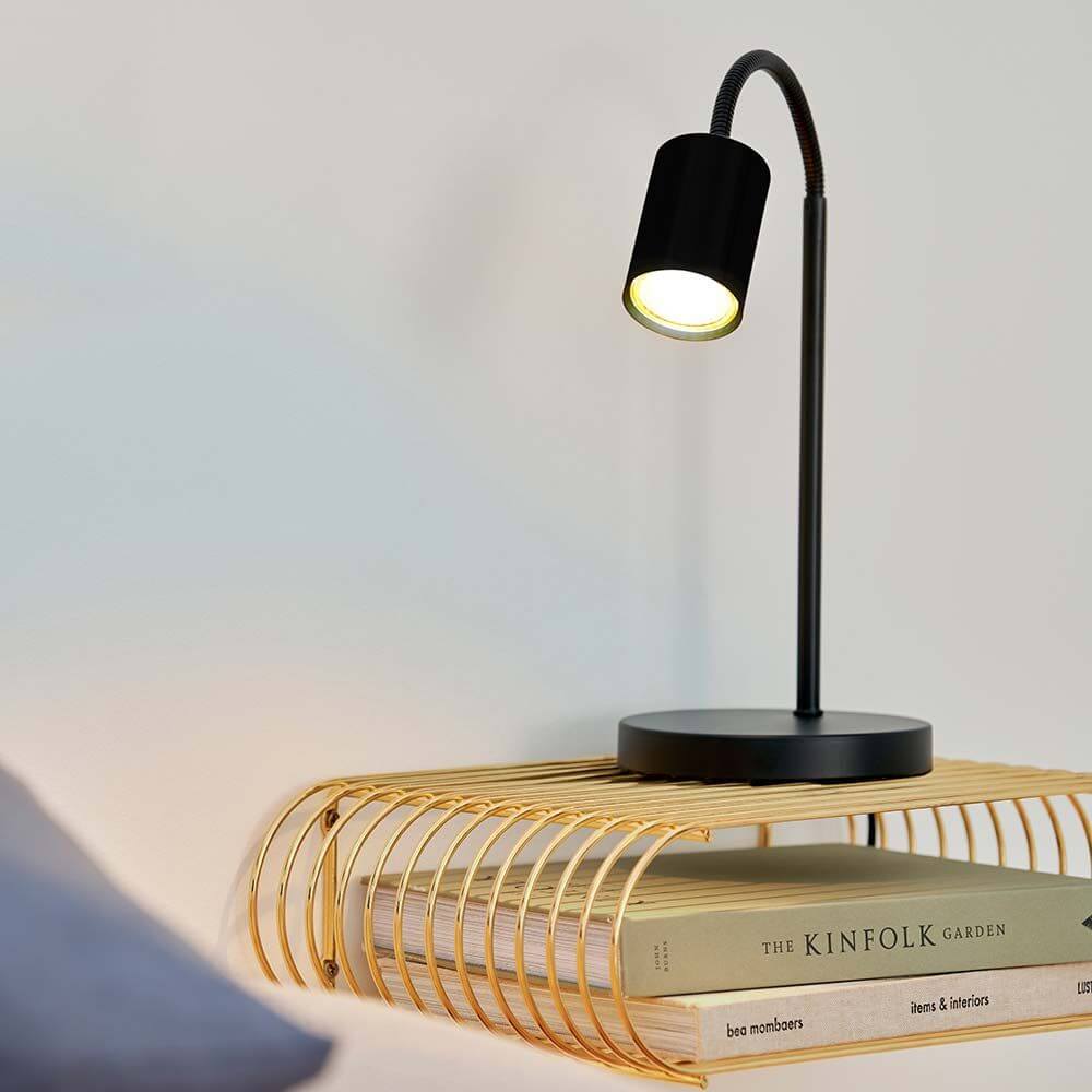 Schwarze Tischleuchte Strahler auf modernem Tisch mit Bücherablage, ideal für Lesen und Arbeiten.