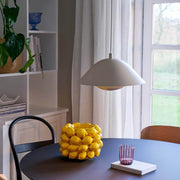 Freya pendant light above a dining table with yellow lemons and colorful glass, Scandinavian design.