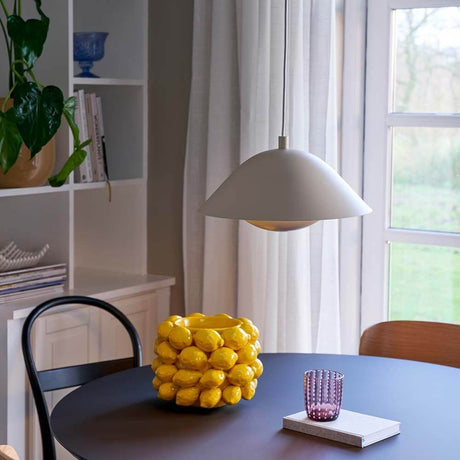 Freya Hängeleuchte über einem Esstisch mit gelben Zitronen und buntem Glas, skandinavisches Design.