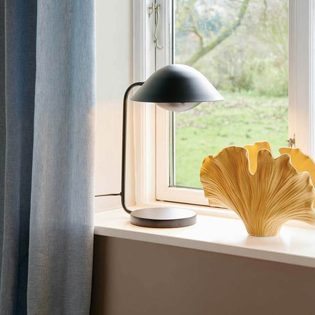 Lampe de table Freya sur un rebord de fenêtre à côté d’un bol décoratif dans un espace de vie scandinave.