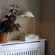 Freya Tischleuchte auf einem Tisch mit Pflanzen und Büchern, skandinavisches Design und elegante Silhouette.