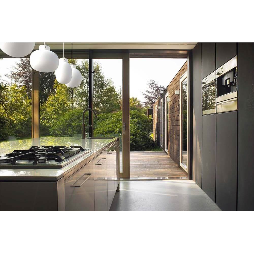 Moderne Küche mit Blick auf den Garten, elegante Ausstattung und großzügige Fensterflächen.