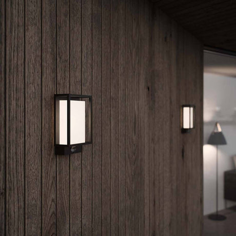 LED Sensor-Wandlampe Nestor IP44 Dimmbar Schwarz an einer Holzwand montiert.