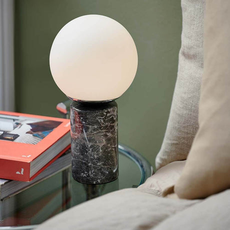 Lilly marble table lamp on a table, combined with a white lampshade and modern marble base.