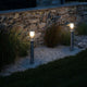 Linton Pollerleuchte IP54 im Garten mit indirektem Licht und elegantem Design neben Steinmauer