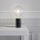 Siv Marmor Tischleuchte Schwarz auf einem Tisch mit warmem Licht und stylischem, modernem Design.