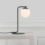 Tischlampe Grant Schwarz, Opal Weiß auf einem Tisch mit eleganter, minimalistischer Gestaltung.