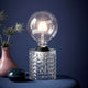 Bordlampe Hollywood Klar med skinnende glasskropp og stilfull lampeskjerm på et bord.