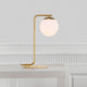 Tischleuchte Grant Messing, Opal Weiß auf einem Tisch, mit eleganter Glaskuppel und modernem Design.