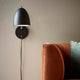 Wandlampe Alexander Schwarz an einer Wand über einem bequemen Sofa, elegantes und modernes Design.