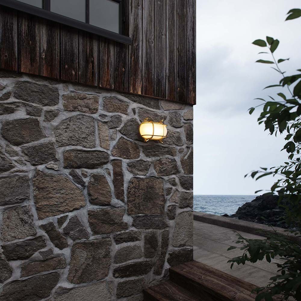 Helford IP64 Schiffslampe aus Messing an einer Steinwand, ideal für maritime Außenbereiche.