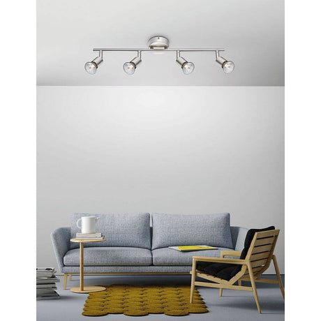 Projecteur de plafond Base à 4 lampes en métal dans un design de salon moderne avec un canapé et une chaise stylés.
