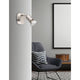 Base Wandspot: moderner Wandstrahler aus Metall mit satiniertem Nickel-Finish über Sessel im Schlafzimmerambiente