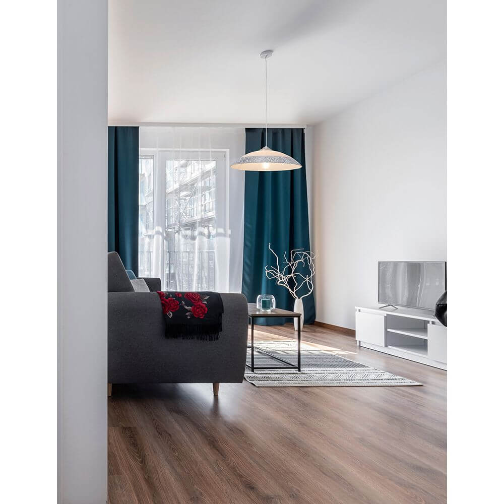 Benito Hängelampe aus Glas hängt elegant im Wohnzimmer über einem modernen Sofa mit Dekoration.