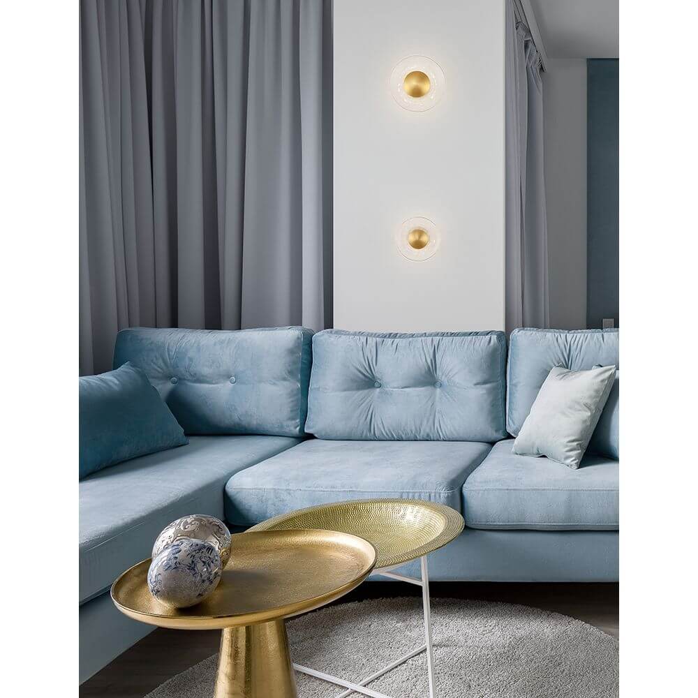 Nova Luce Esil LED Wandlampe Gold, Klar über einem blauen Sofa in modernem Wohnbereich.