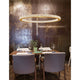 Fiore LED Hängelampe Ø 80cm in antik gold hängt über einem eleganten Esstisch.