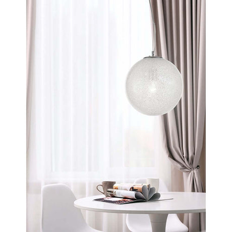 Frozen Kugel pendant lamp in glass hangs above a dining area with elegant furnishings and soft drapes.
