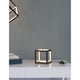 Gabbia LED Würfel Tischlampe auf einem weißen Tisch, modernes Design mit goldenen Akzenten.