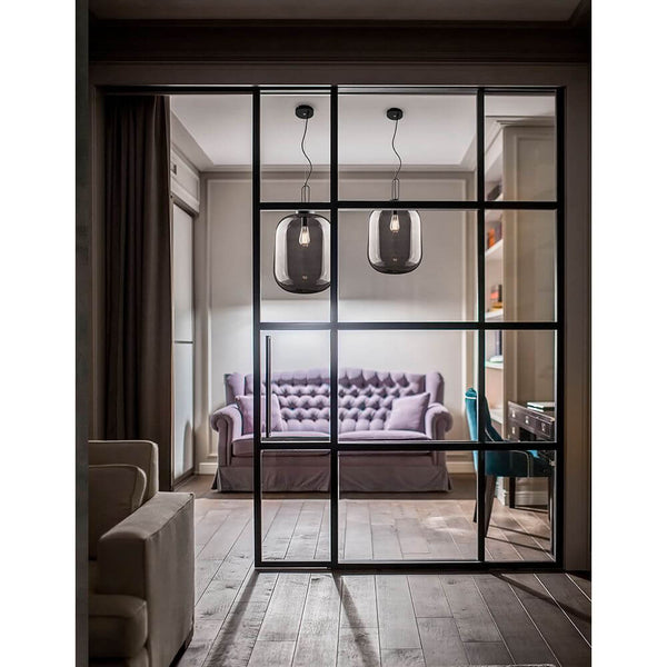 Hunter pendel i røget glas over en stilfuld stue med en elegant sofa.