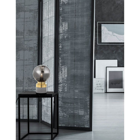 Juliet Glas-Tischlampe Gold auf einem Tisch vor einem dekorativen Raumhintergrund.