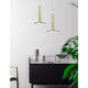 Moderne Palencia LED Pendelleuchte in Gold über einem eleganten Möbelstück mit Pflanzen im Hintergrund.
