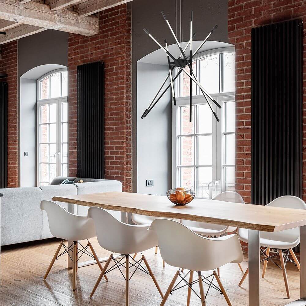 Stilvolle Raccio LED Hängeleuchte über einem modernen Esstisch in elegantem Raum mit roten Ziegelwänden.