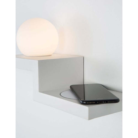 Room LED Wandlampe mit Ladegerät auf einem modernen Wandregal neben einem Smartphone.