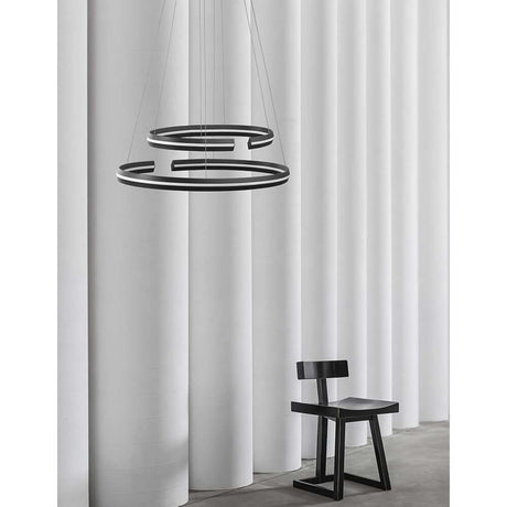 Torrente LED pendant light 2-ring metal, acrylic in a modern living room setup with chair and curtains.