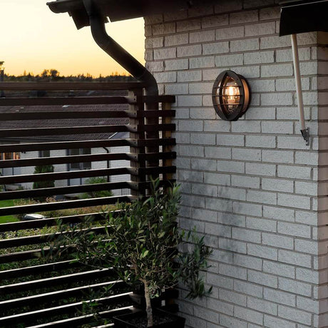 Aplique de pared exterior Oden con enchufe negro, acrílico opalescente montado en una pared de ladrillo.