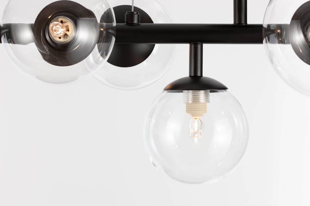 Detailansicht der Odillia Pendelleuchte G9 7-flammig mit transparenter Glaskugel und mattschwarzem Gestell.