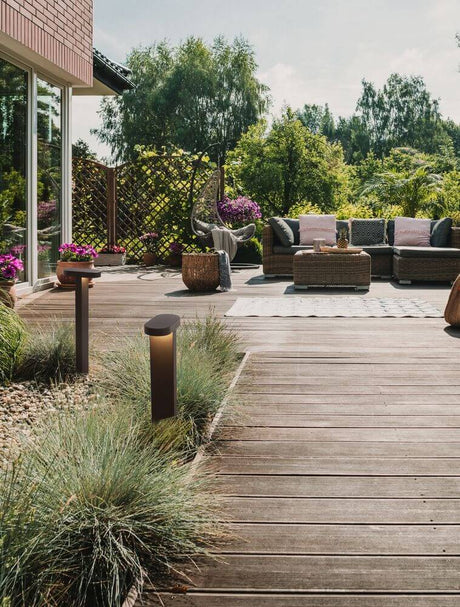 Ofir LED outdoor path light 3000K black IP54 on a terrace with garden plants and a seating area.