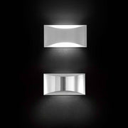 Oluce LED Wandleuchte Kelly Weiß in modernem Design, zwei elegante Leuchten an einer dunklen Wand.