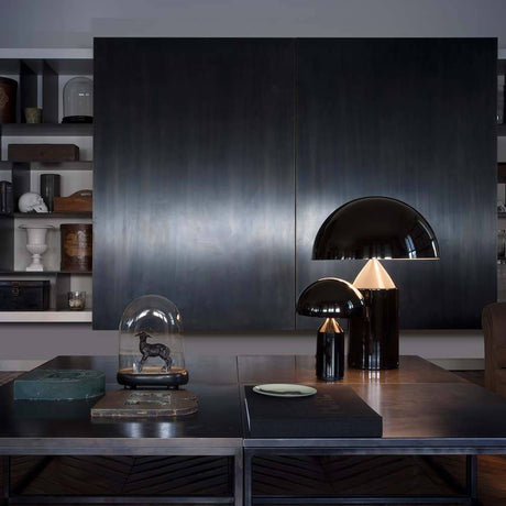 Oluce Tischlampe Atollo 70 Schwarz auf einem eleganten Tisch mit modernen Möbeln im Hintergrund.