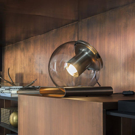 Oluce table lamp The Globe antique gold-coloured on a wooden table with a glossy surface.