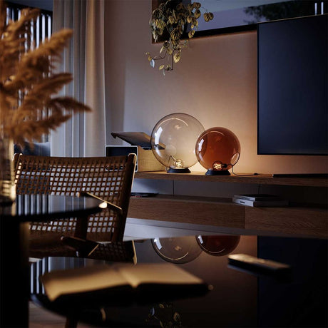 s.luce Orb Glaskugel Tischlampe auf einem stilvollen Tisch mit sanfter Beleuchtung.