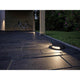LED Plug & Shine Aufbauleuchte IP67 24V 2x350lm 3000K Anthrazit auf einem gepflasterten Weg bei Nacht.