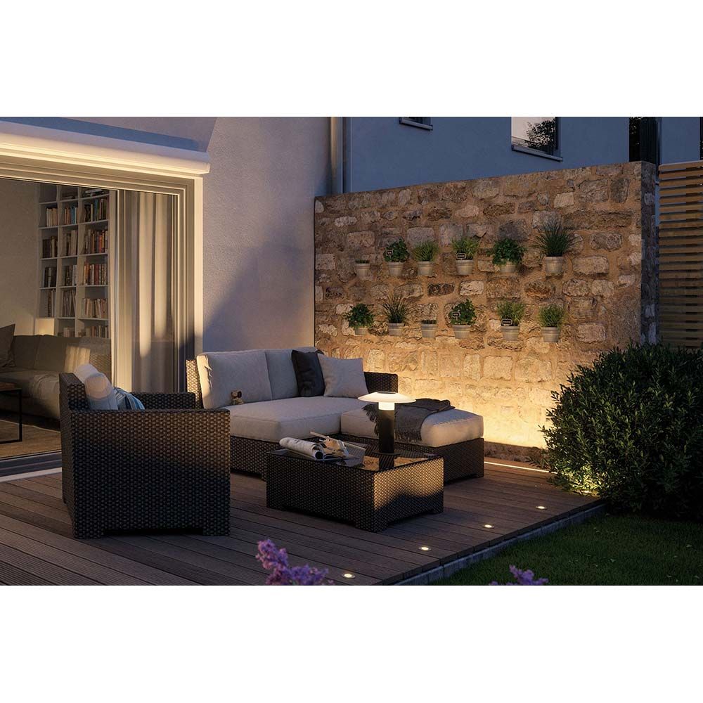 Gemütlicher Außenbereich mit Gartenmöbeln und betonierter Wandbeleuchtung, ideal für entspannte Abende im Freien.