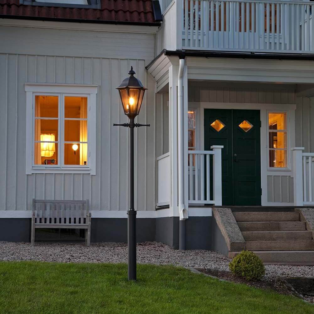 Pallas Mastleuchte 260cm Schwarz, rauchfarbenes Acrylglas vor einem Haus mit Veranda.