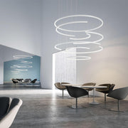 Panzeri Brooklyn Halb-Ring LED-Pendelleuchte in modernen Büroumgebung mit stilvollen Sitzmöbeln.