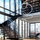 Moderne Panzeri Brooklyn LED-Ring Pendelleuchte in stilvollem Wohnraum mit Treppe und großen Fenstern.